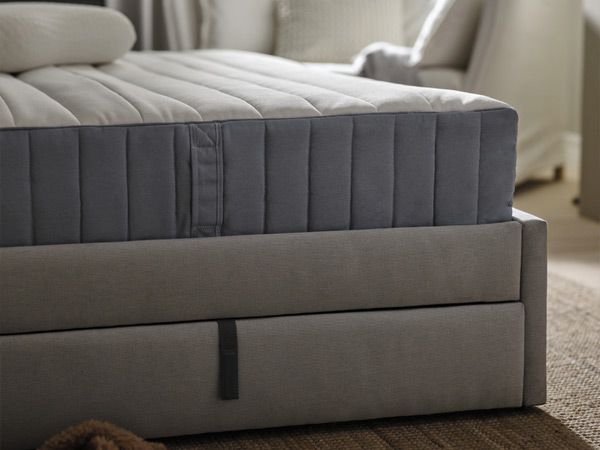 Quilted mattress on box spring with strap, close-up view