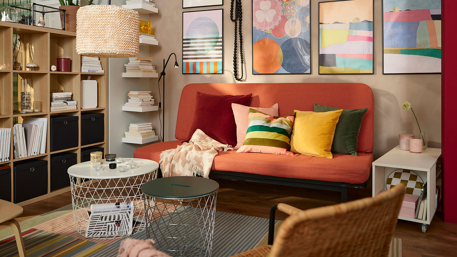 Colorful environment with a minimalist sofa with several multicolored cushions, 70's style, there is an open shelf of pine wood,