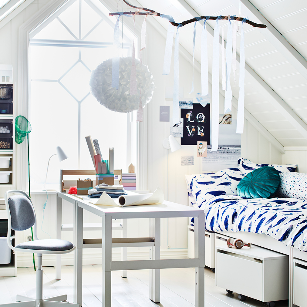 A bedroom with a PAHL desk and an ORFJÄLL desk chair in the middle, and a SLAKT bed with 3 storage boxes on the right.