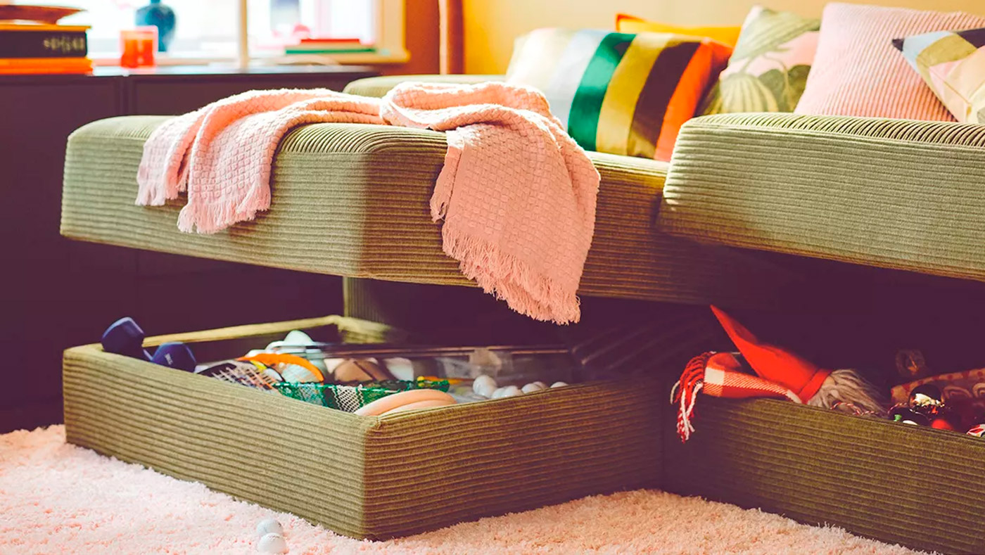 An olive-green modular sofa with hidden storage reveals colorful blankets and items. Homely, functional ambiance.