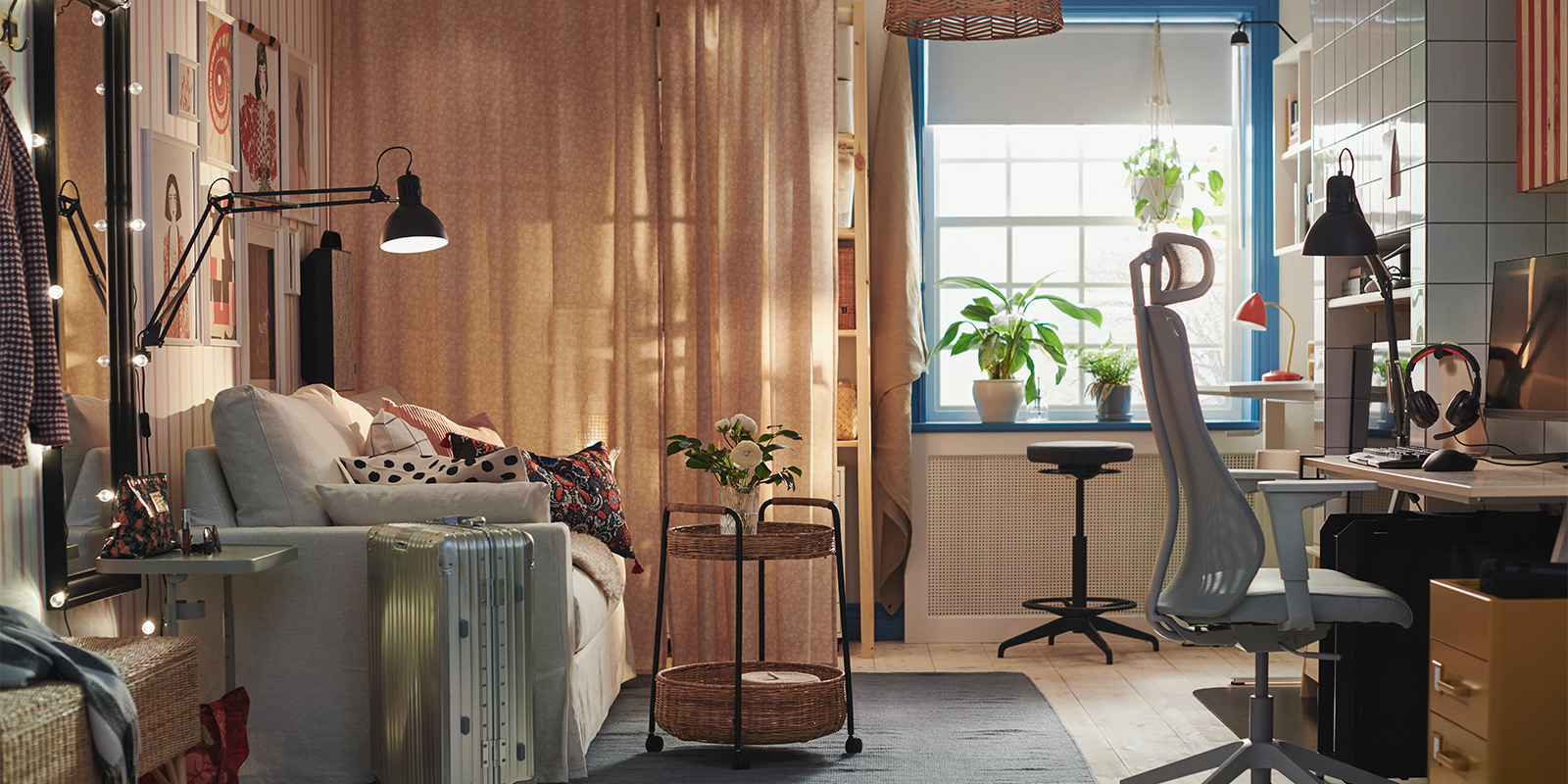 Cozy room with a study area, sofa, plants, and natural light coming through a large window.