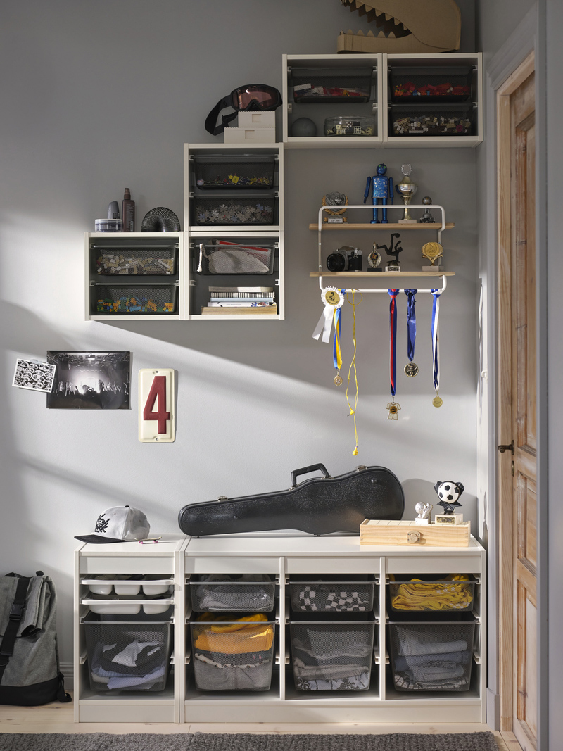 Organized youth bedroom with white modular shelves filled with toy boxes and personal items. A functional and modern ambiance for a teenager.