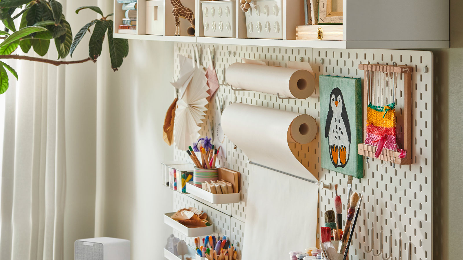 Creative wall with art supplies, paper rolls, and crafts neatly arranged on pegboard.