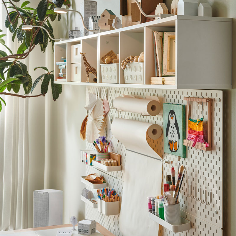 Creative wall with art supplies, paper rolls, and crafts neatly arranged on pegboard.