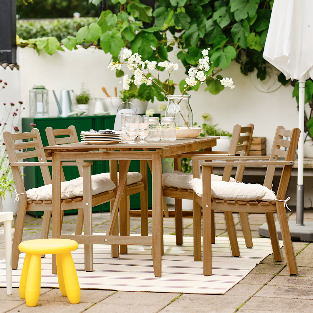 Barbecue area, with an outdoor table with 4 chairs, in front a small plastic dining area for children, in the background a barbecue and a closed parasol.