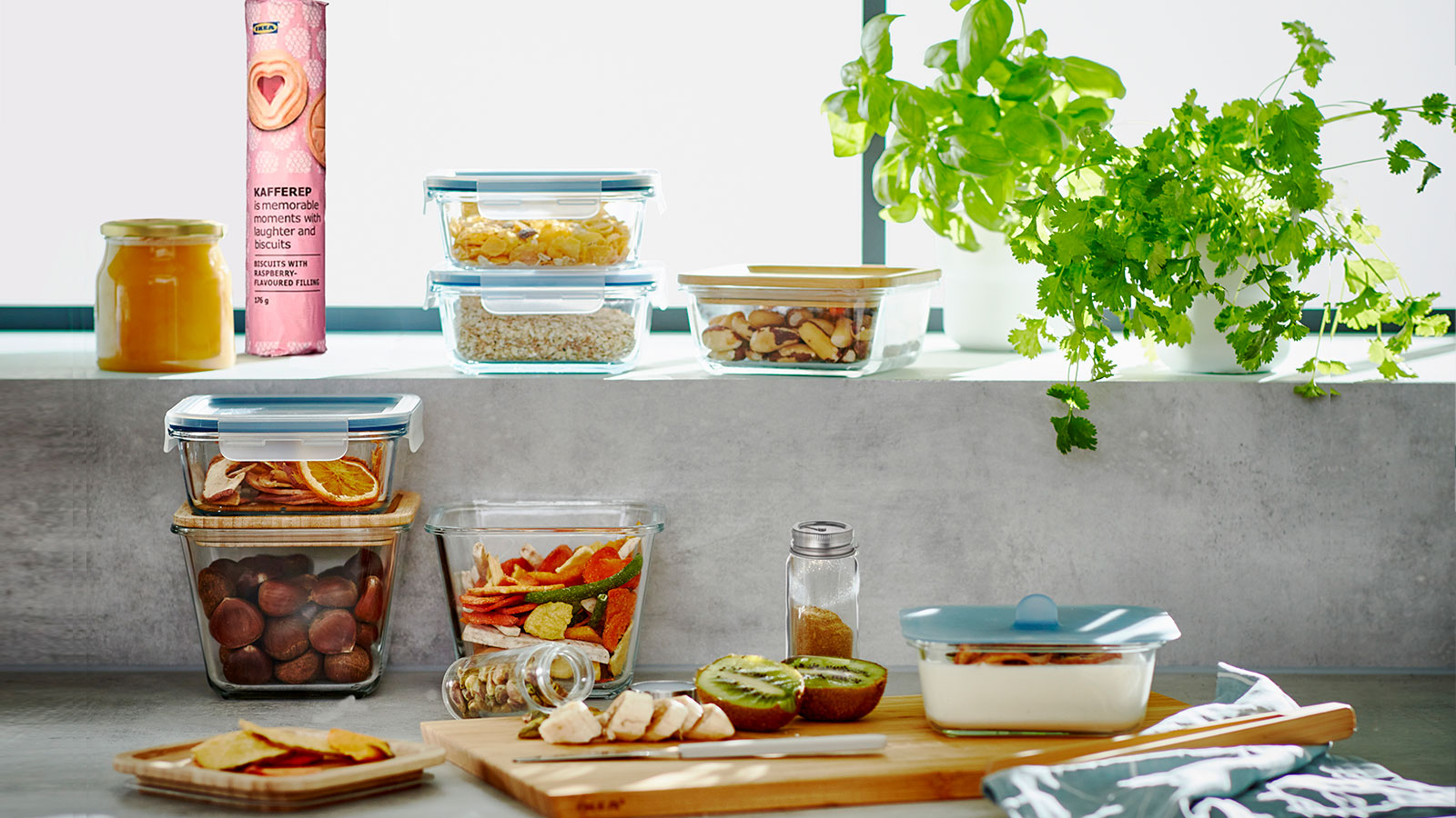 Rustic outdoor kitchen with food containers, sliced fruits, preserves, and a cutting board with knife in a cozy, natural setting.