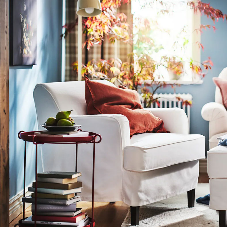 Traditional style reading corner with comfortable chair, cushions and blankets, candles and flowers for a relaxing atmosphere