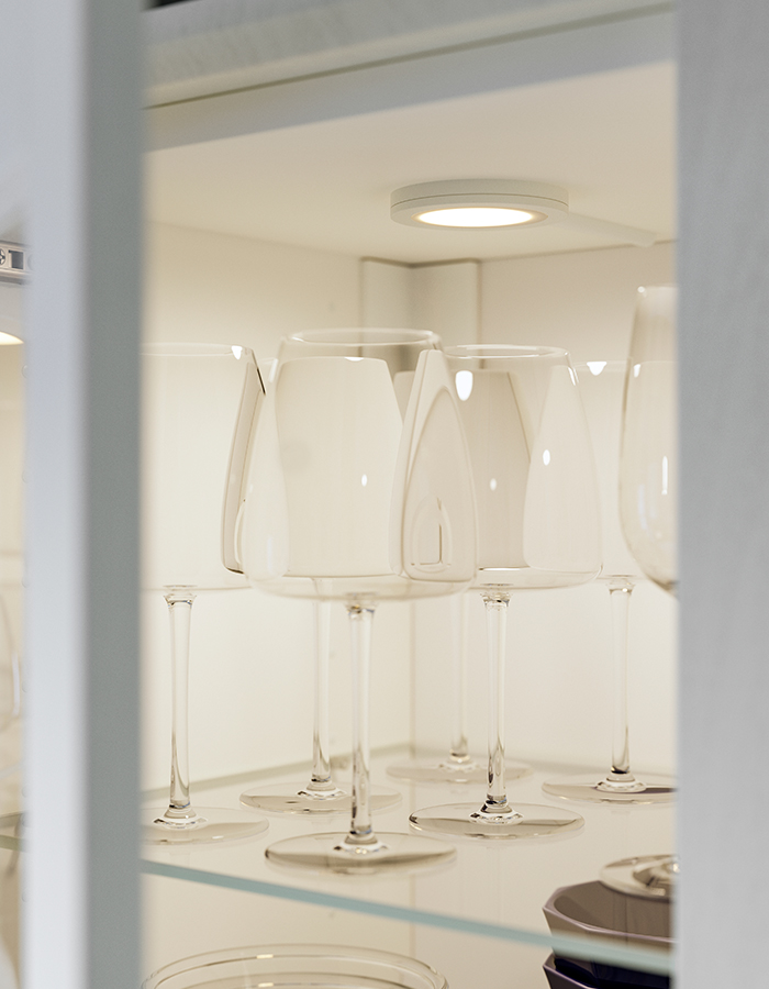 Cabinet with wood and glass door featuring a DYRGRIP wine glass, illuminated by MITTLED LED lighting.
