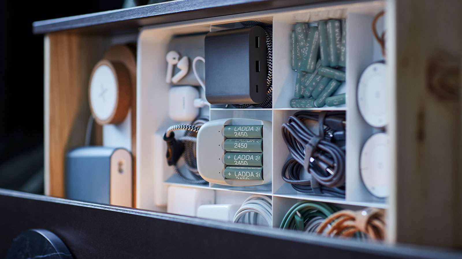 Drawer neatly organized with batteries, cables, chargers, and tech accessories in sections.