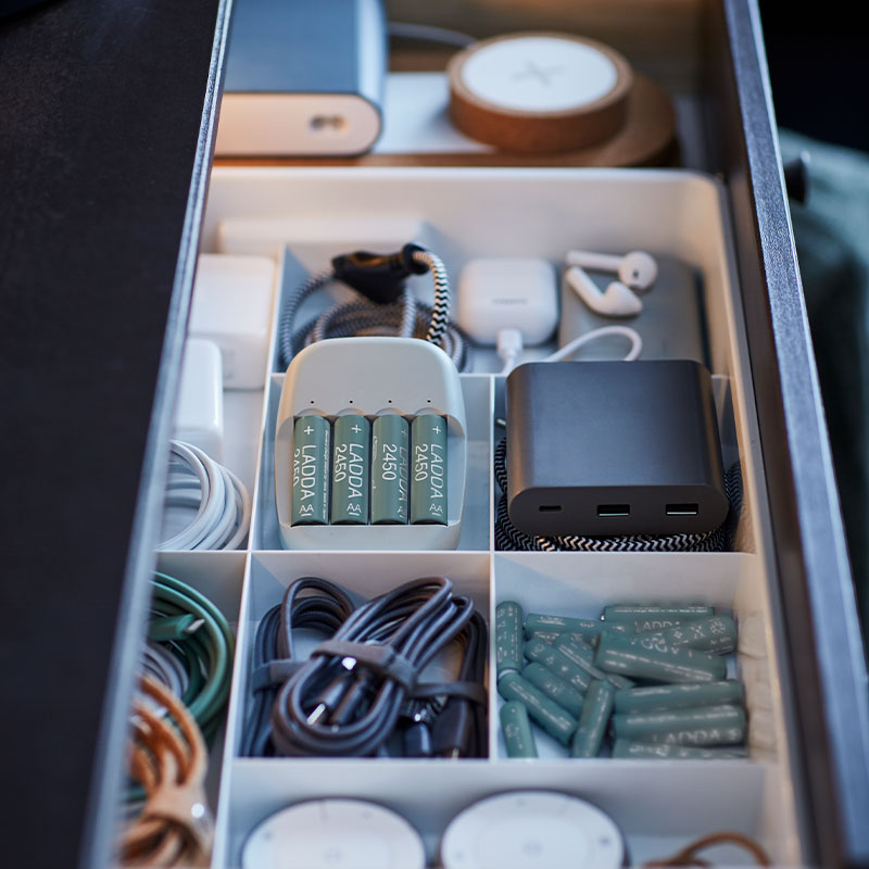 Drawer neatly organized with batteries, cables, chargers, and tech accessories in sections.