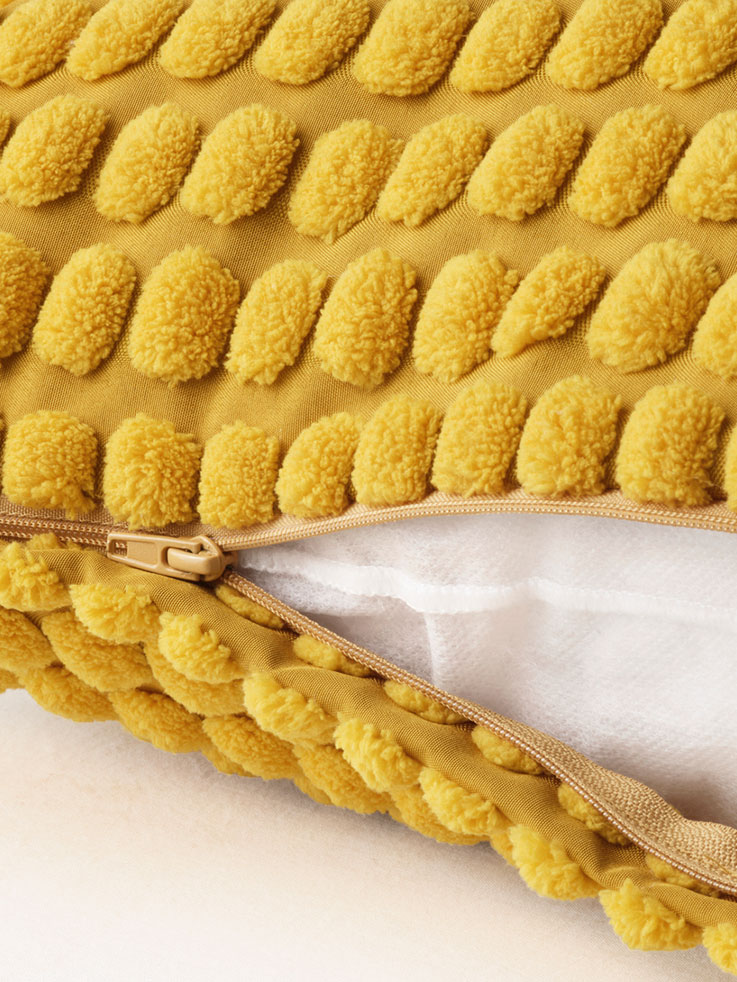 Close-up of the closure of a yellow cushion, you can see the fluffy texture of the cover.