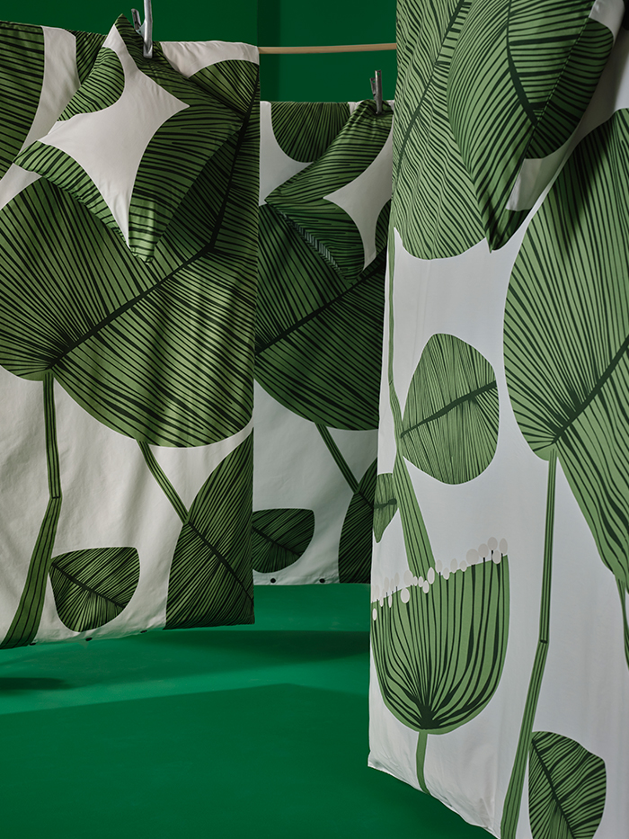 White curtains with large printed green leaves, in a green background environment
