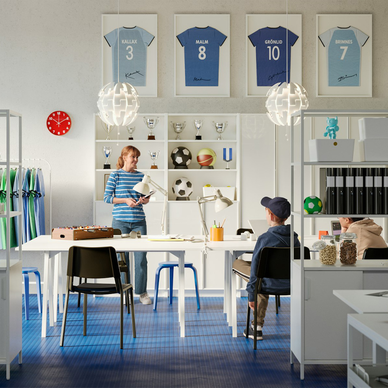 Children's study and creativity room, there are modern bookshelves with books, there are desks with computers and at the back shelves with sports trophies and framed soccer balls and soccer jerseys.