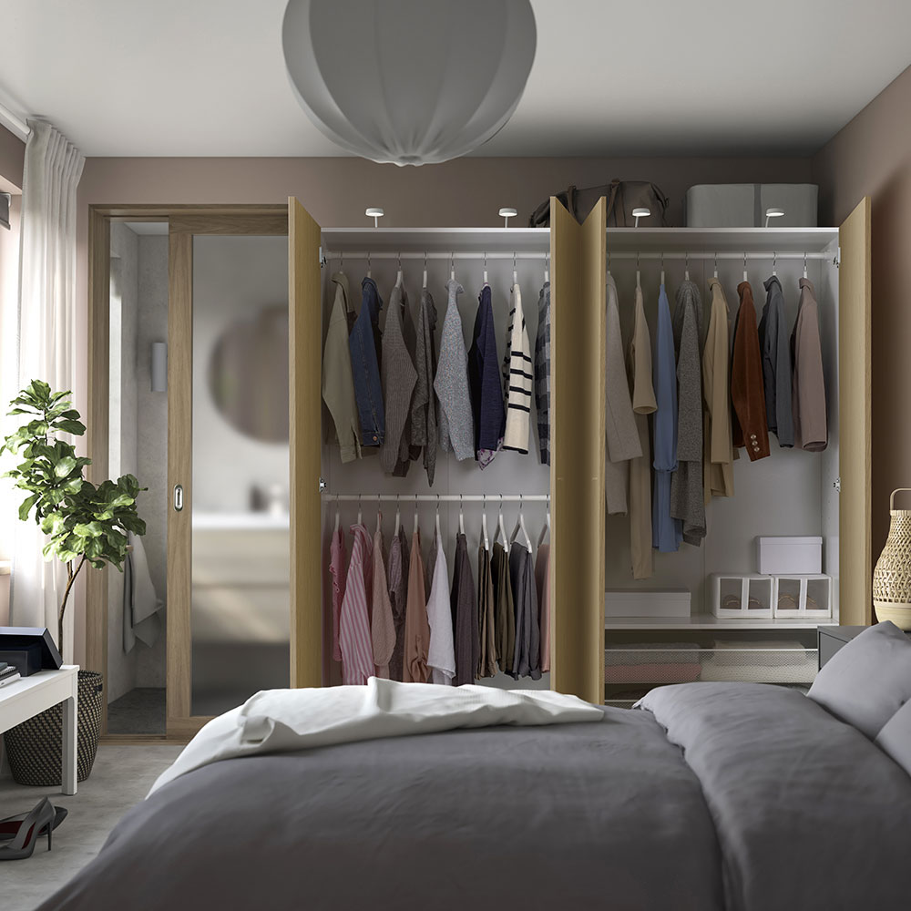 A bedroom with a PAX PAX/STORKLINTA wardrobe filled with clothes hanging from a BOOMERANG hanger.
