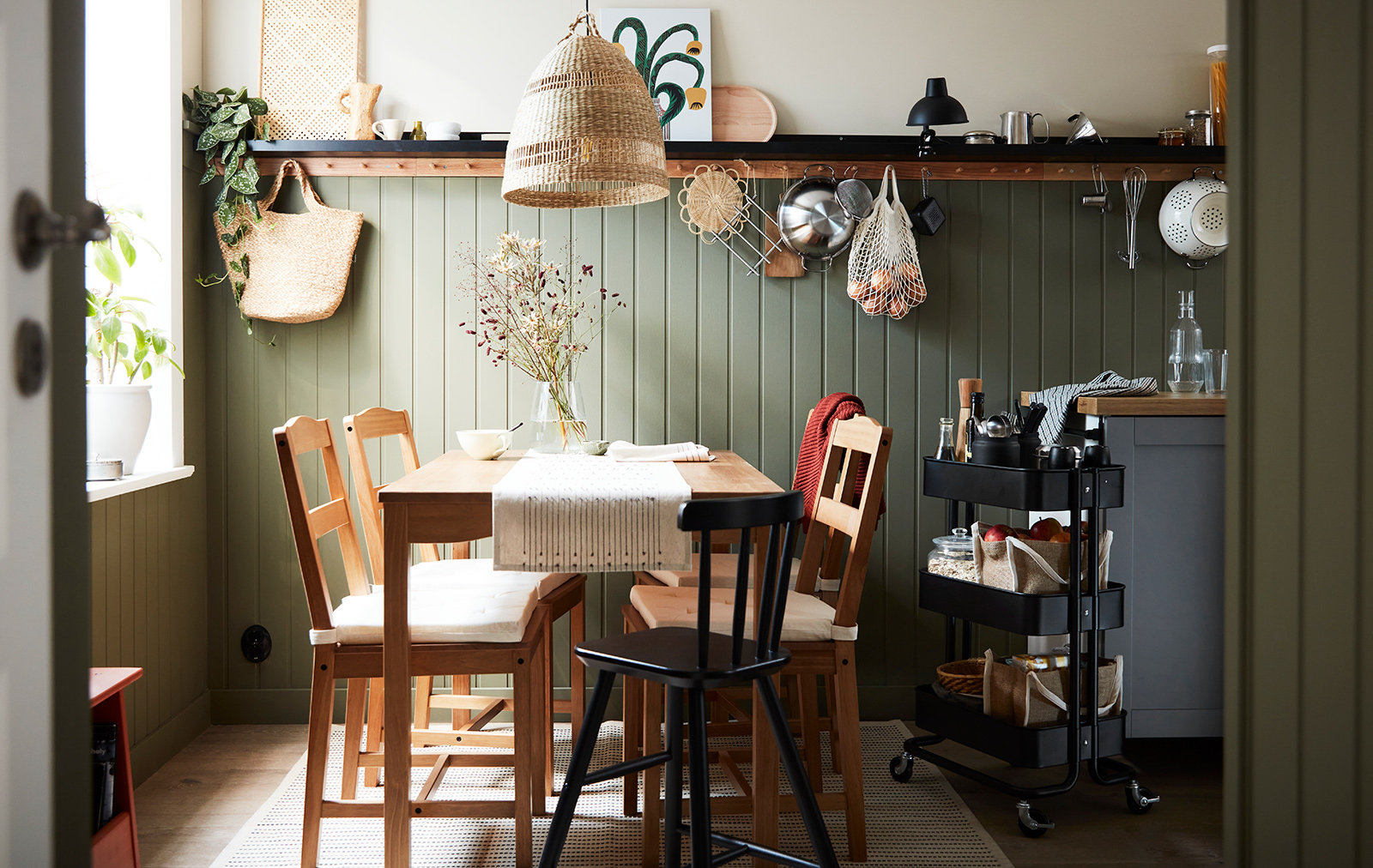 Vintage style dining room, oak style table and chairs, a large window, a woven hanging lamp, cozy and quiet atmosphere.