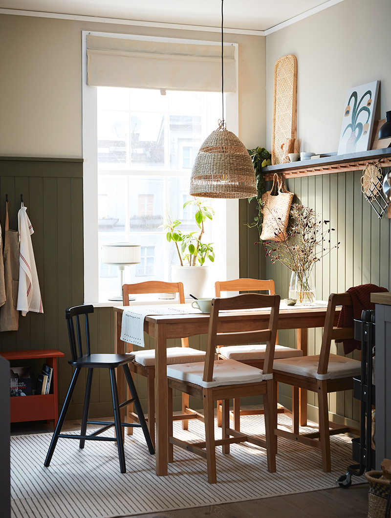 Vintage style dining room, oak style table and chairs, a large window, a woven hanging lamp, cozy and quiet atmosphere.