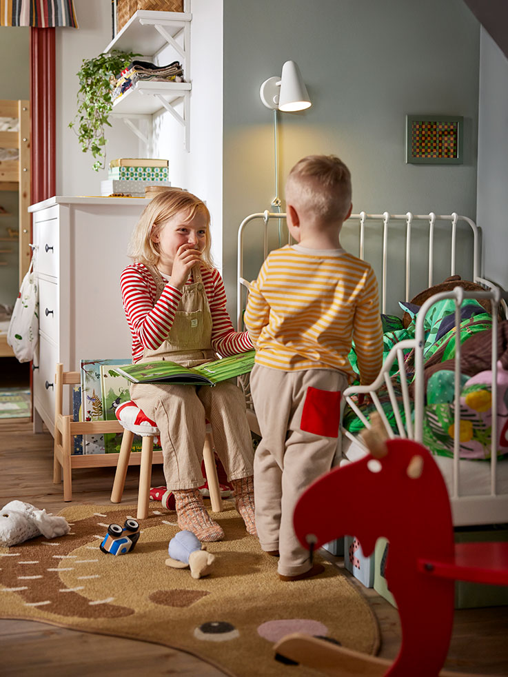  Two children spending time with a MINNEN extendable bed, SKOGSDUVA stool converter, and KOPPANG chest of drawers.