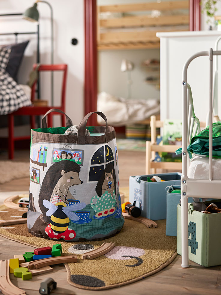  Children's room with a SKOGSDUVA storage bag next to a MINNEN extendable bed and a FLISAT book display.