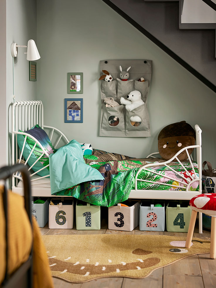  Children's room with a MINNEN extendable bed featuring a SKOGSDUVA duvet, next to a stool with SKOGSDUVA cover and a FUBBLA wall lamp.