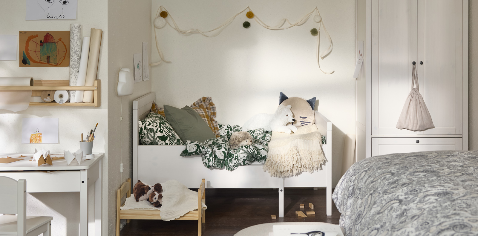  Cozy kids' room with white bed, stuffed animals, and soft-toned decorative touches.