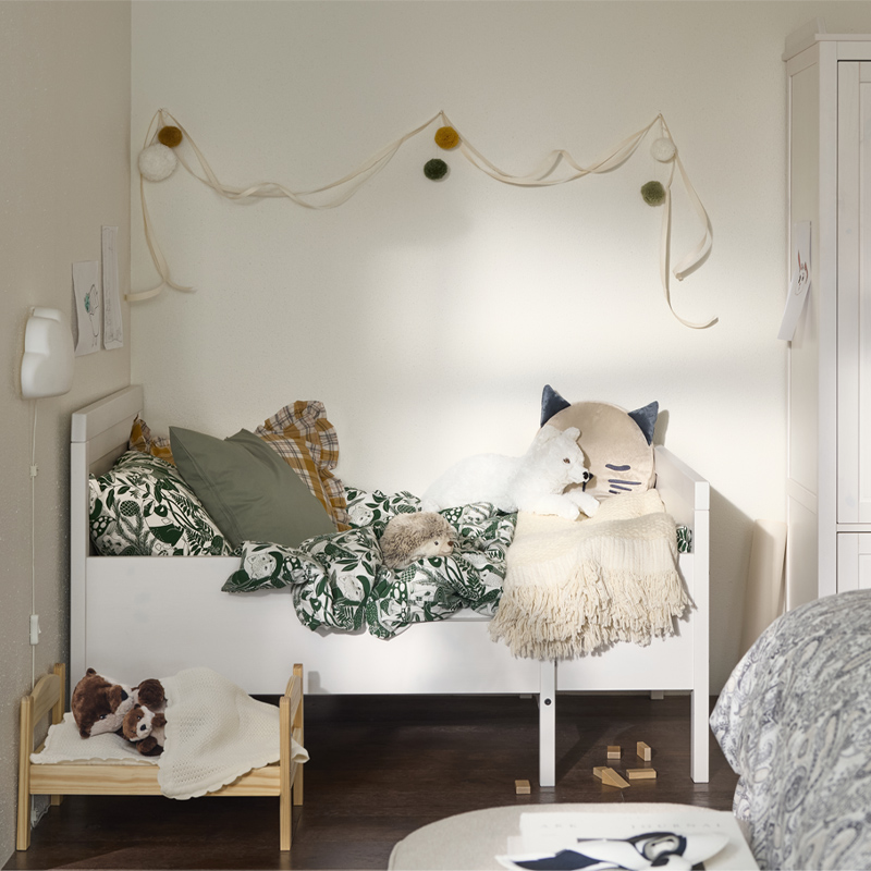  Cozy kids' room with white bed, stuffed animals, and soft-toned decorative touches.