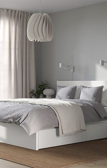 Minimalist bedroom with white storage bed, grey bedding, and Scandinavian-style pendant lamp.