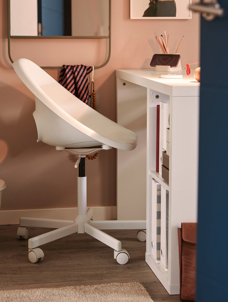  White office chair on wheels, in pink room. White desk with objects. Study ambiance.
