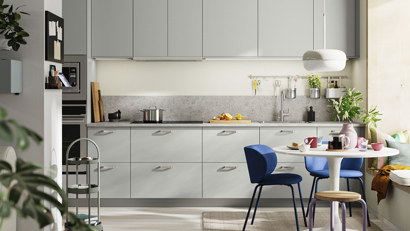 Modern gray and white kitchen, round table with blue chairs. Bright and contemporary atmosphere.