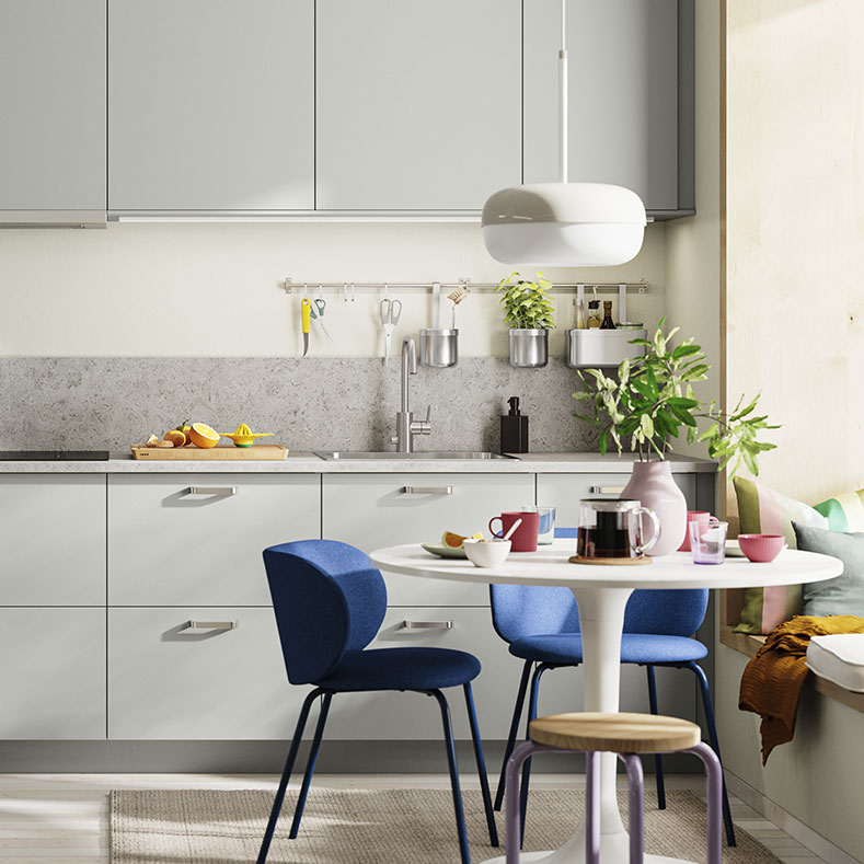 Modern gray and white kitchen, round table with blue chairs. Bright and contemporary atmosphere.
