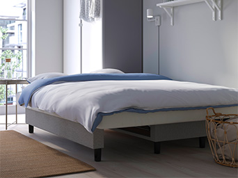 A neatly made bed with white and blue bedding in a modern, minimalistic bedroom.