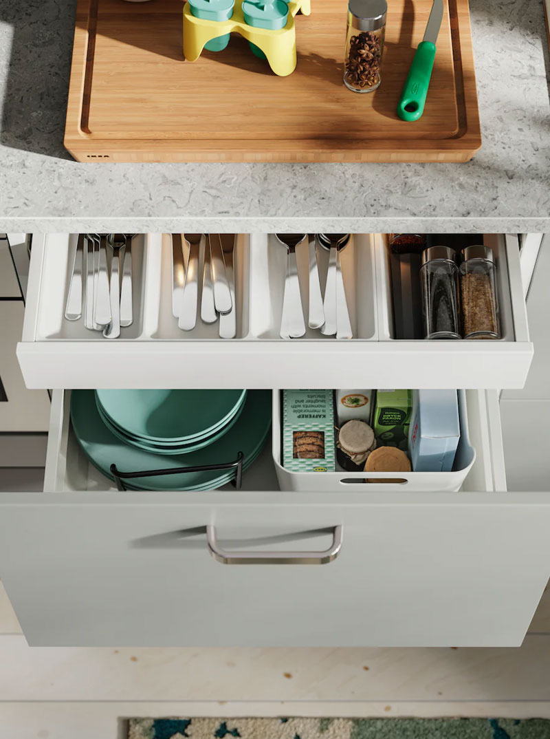Open kitchen drawers with organized cutlery, plates, and spices. Functional kitchen ambiance.