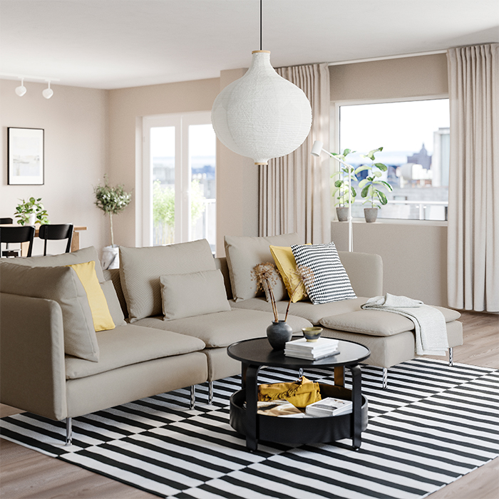 Modern-style gray sofa in a bright living room with beige tones, a round black coffee table, and a black and white striped rug.