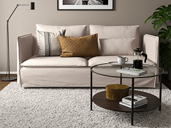 Modern-style gray sofa in a bright living room with beige tones, a round black coffee table.