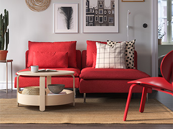 Modern red sofa with striped and dotted cushions, round wooden coffee table in a modern style, and four framed photo prints on the wall.
