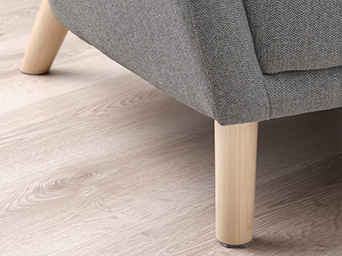 Close-up of wooden legs on a grey upholstered armchair