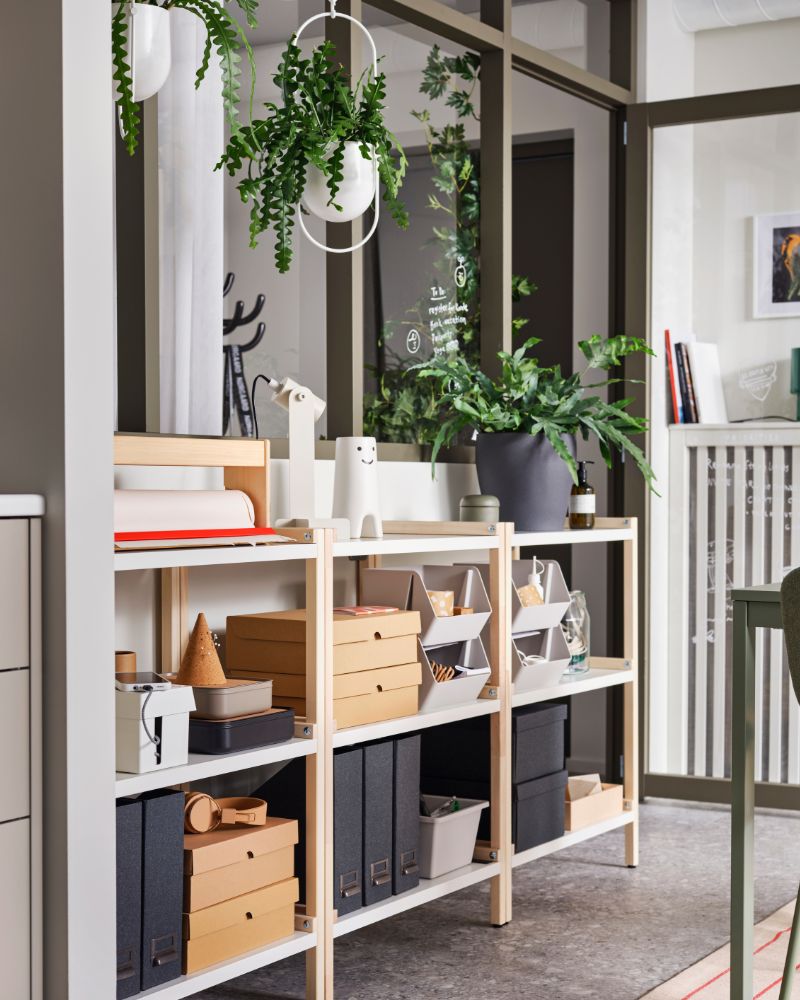 Light wood and white shelving unit with organizing boxes and plants. Modern and tidy ambiance.
