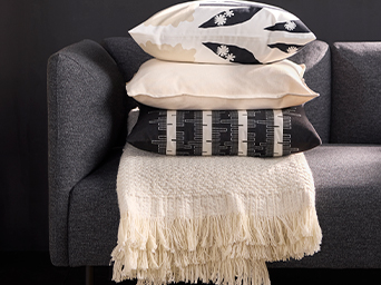 IKEA cushions and blanket stacked on gray sofa. Soft textiles with patterns to add comfort and style to your living room.