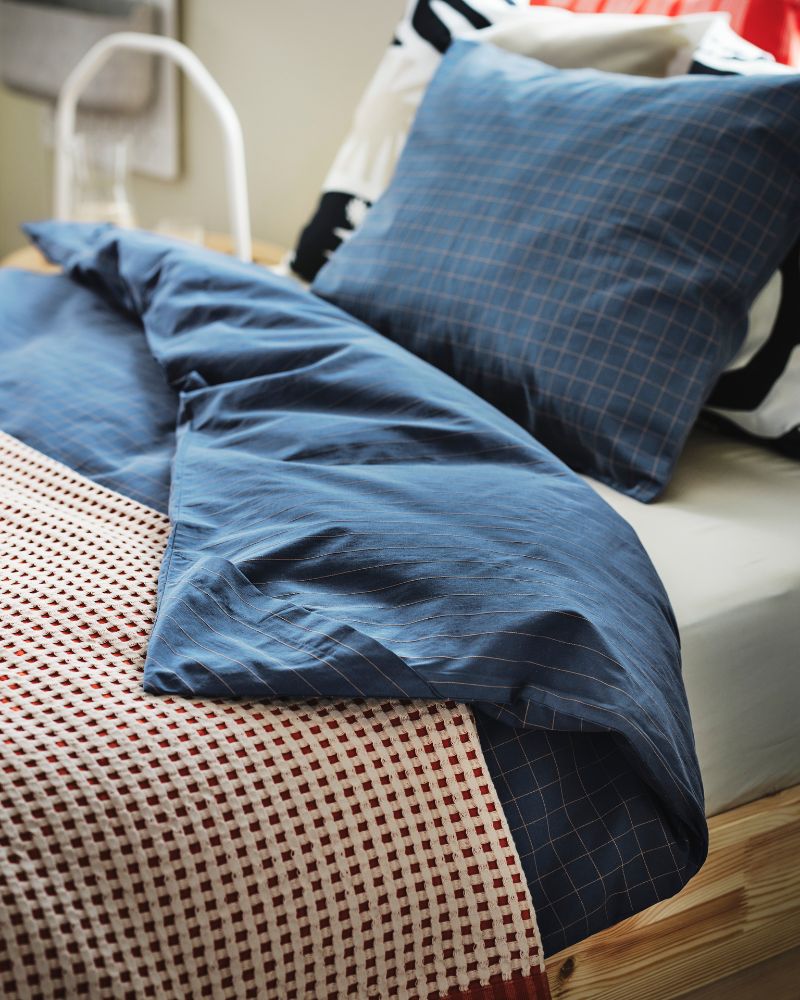 Dark blue/light brown DOFTAKLEJA bed linen on a GLAMBERGET extendable bed with a PELARTUJA bedspread on top.