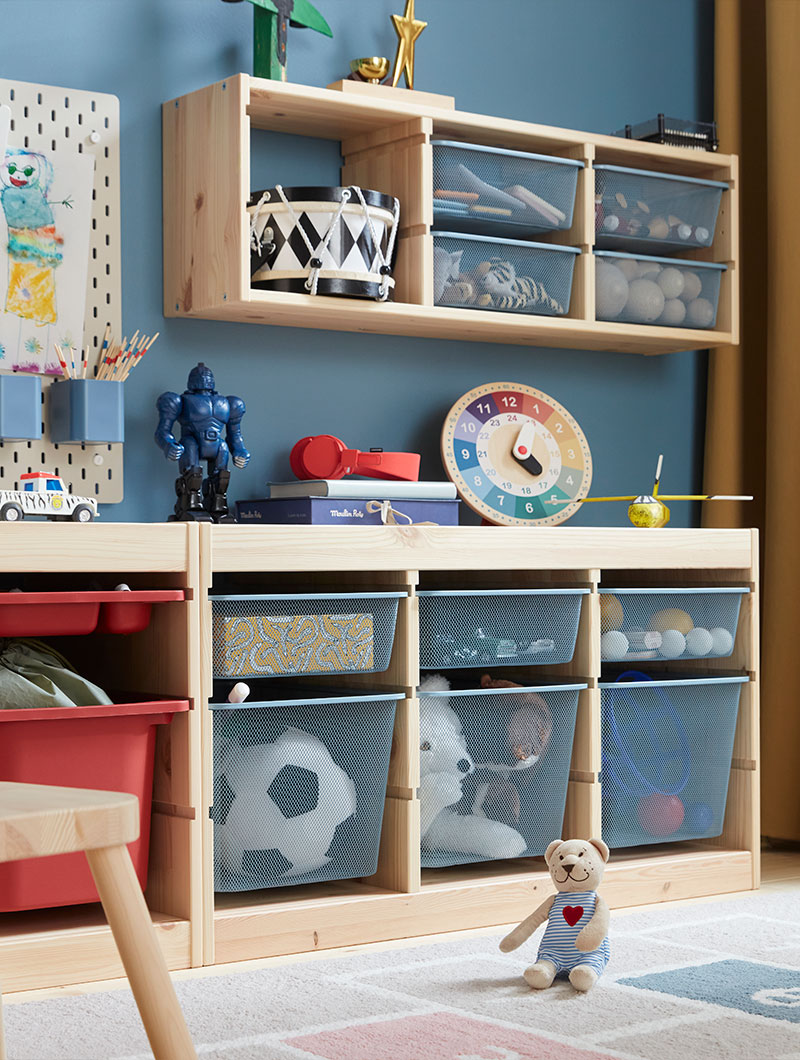 A blue children’s room with TROFAST frames in pine holding grey-blue TROFAST mesh storage boxes with children’s toy