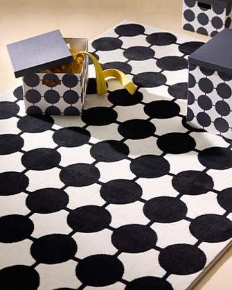 Black and white rug with a circular pattern, paired with matching storage boxes. Organize and decorate your home with smart solutions.
