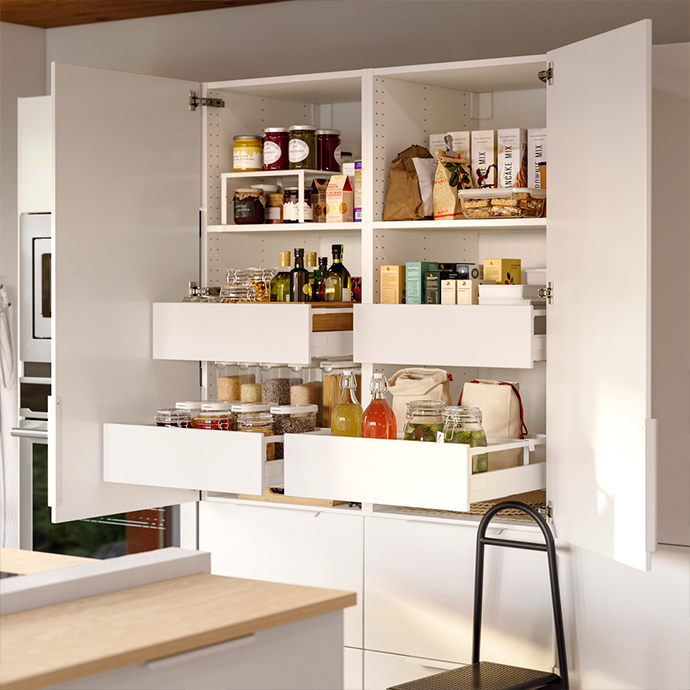 Interior of a white kitchen cabinet with UTRUSTA pull-out shelves and solutions, organizing food and bottles. Maximize your pantry space.