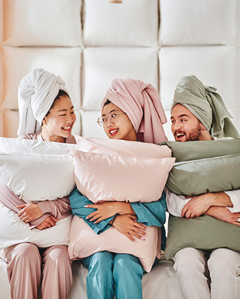 tres personas jóvenes, sosteniendo un par de almohadas cada uno