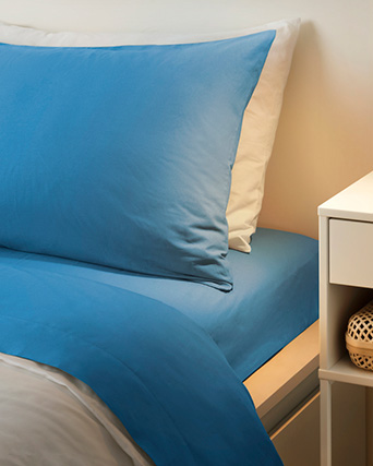 una cama con dos almohadas, vestida con ropa de cama color azul