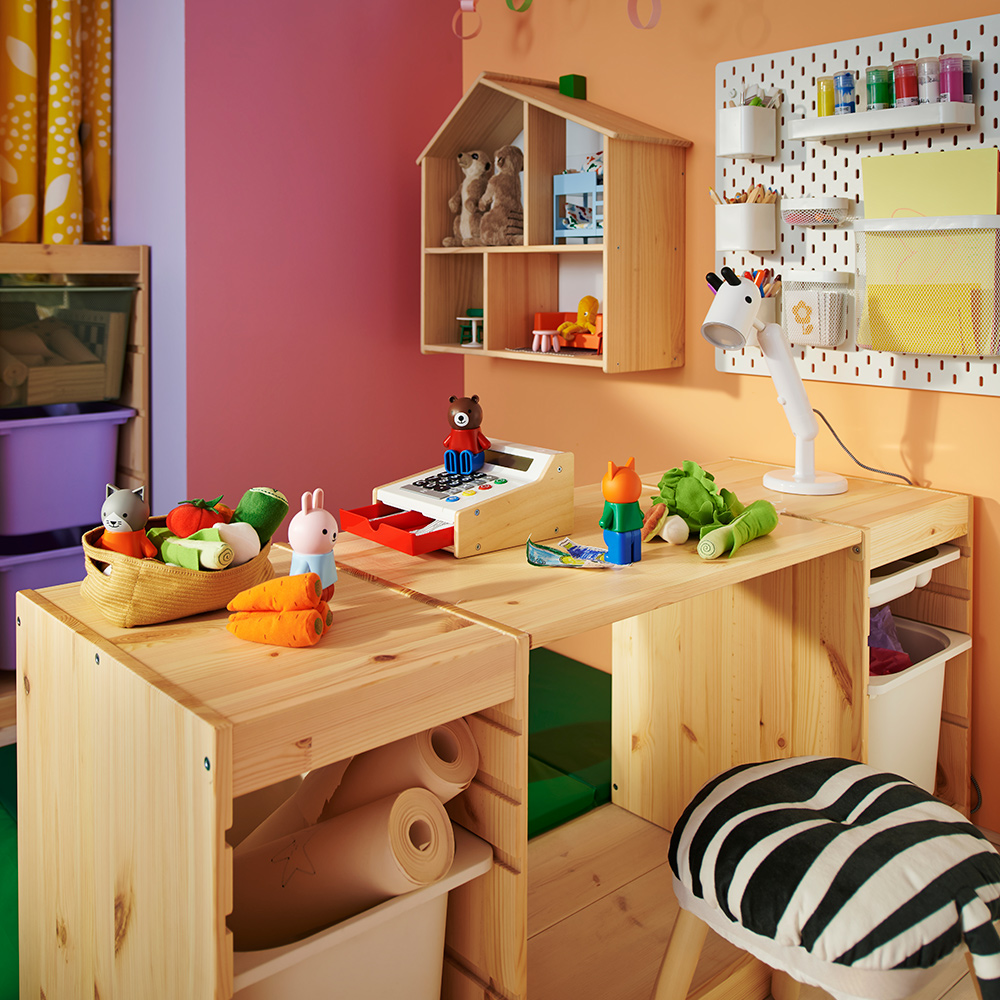 Una encimera TROFAST de pino blanqueado claro y dos estructuras combinadas para crear un escritorio en un colorido dormitorio infantil.