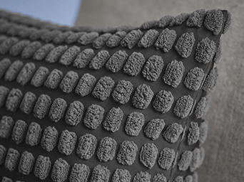 Primer plano de una funda de cojín gris oscuro con una densa textura de relieve tipo "popcorn".