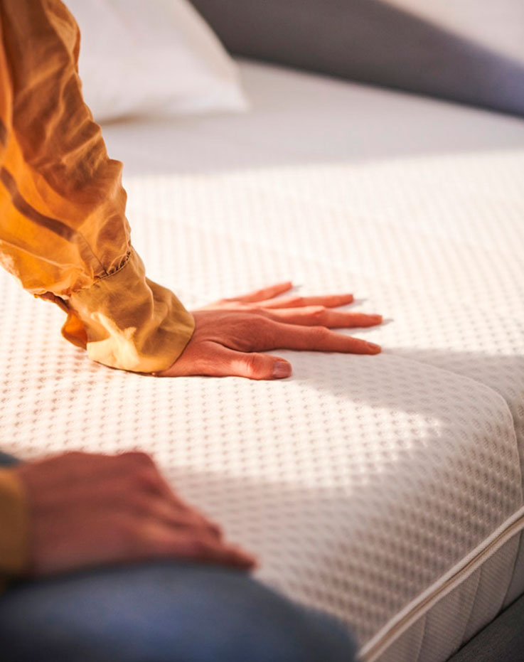 One-handed shot measuring the thickness and softness of a mattress