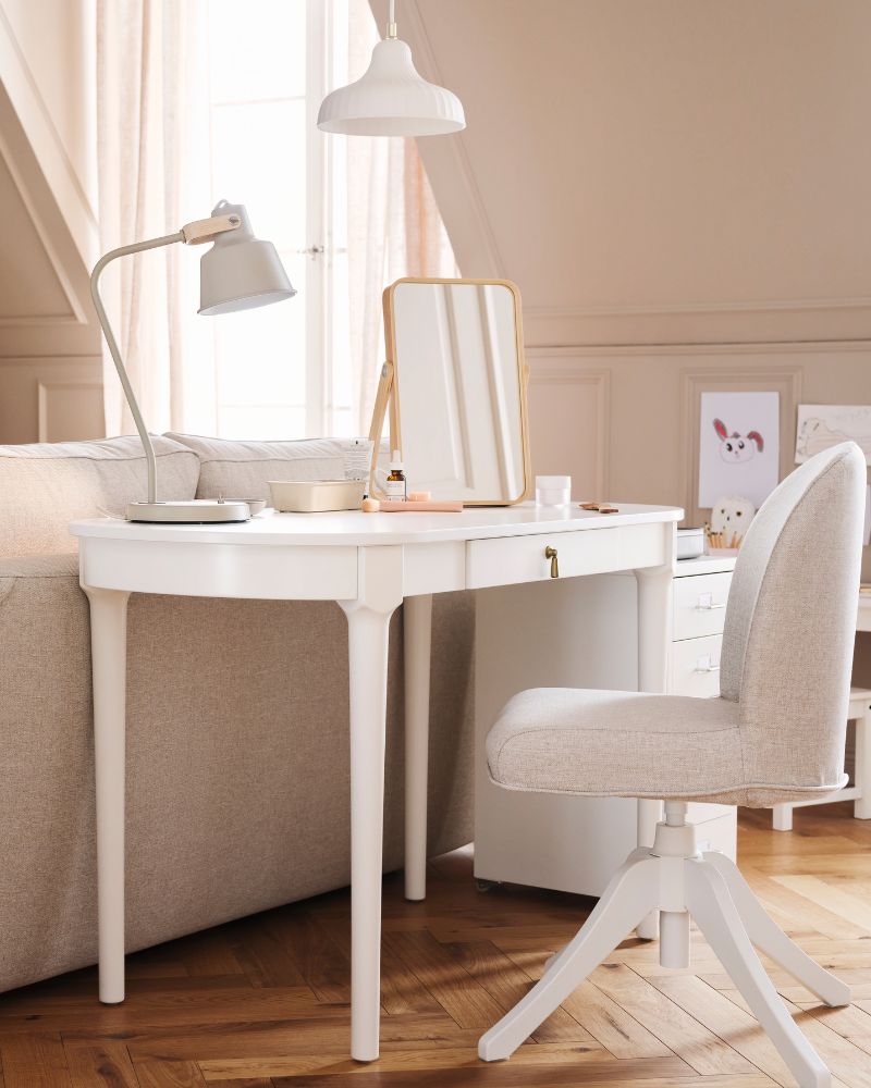 A white ROSENTORP desk and a ROSENTORP swivel chair stand behind an EKHOLMA 2-seat sofa-bed in a multipurpose living room.