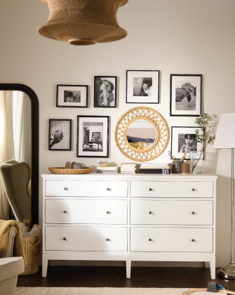 White dresser with a mirror and framed wall art.