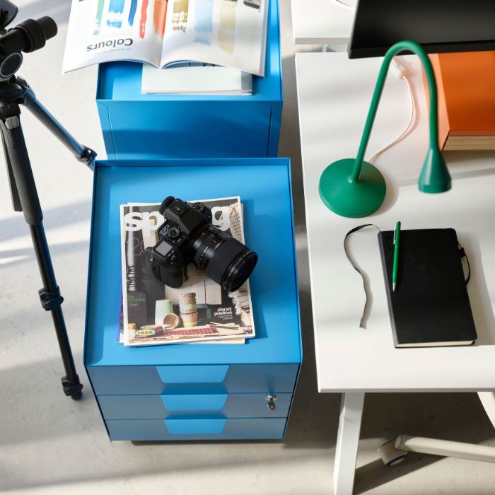 Modern workspace with TROTTEN desks, NÄVLINGE lamp, storage drawers and camera setup for a clean and functional office.