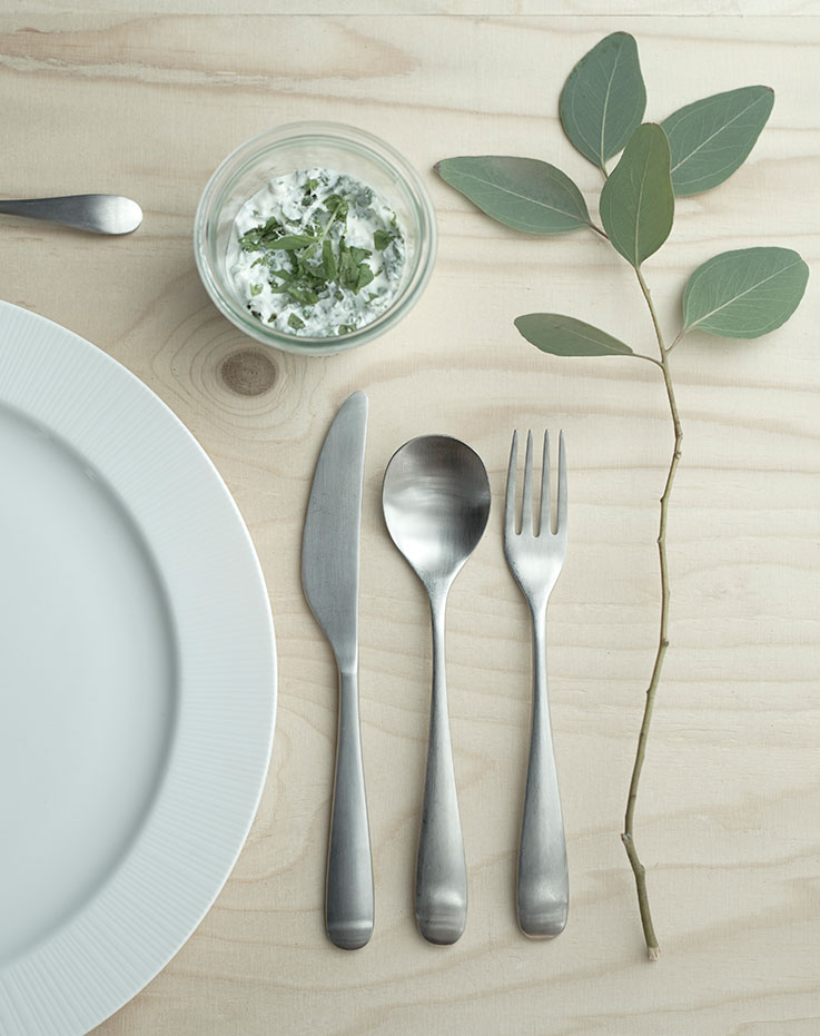 Plate and silverware on a table, ready to be used.